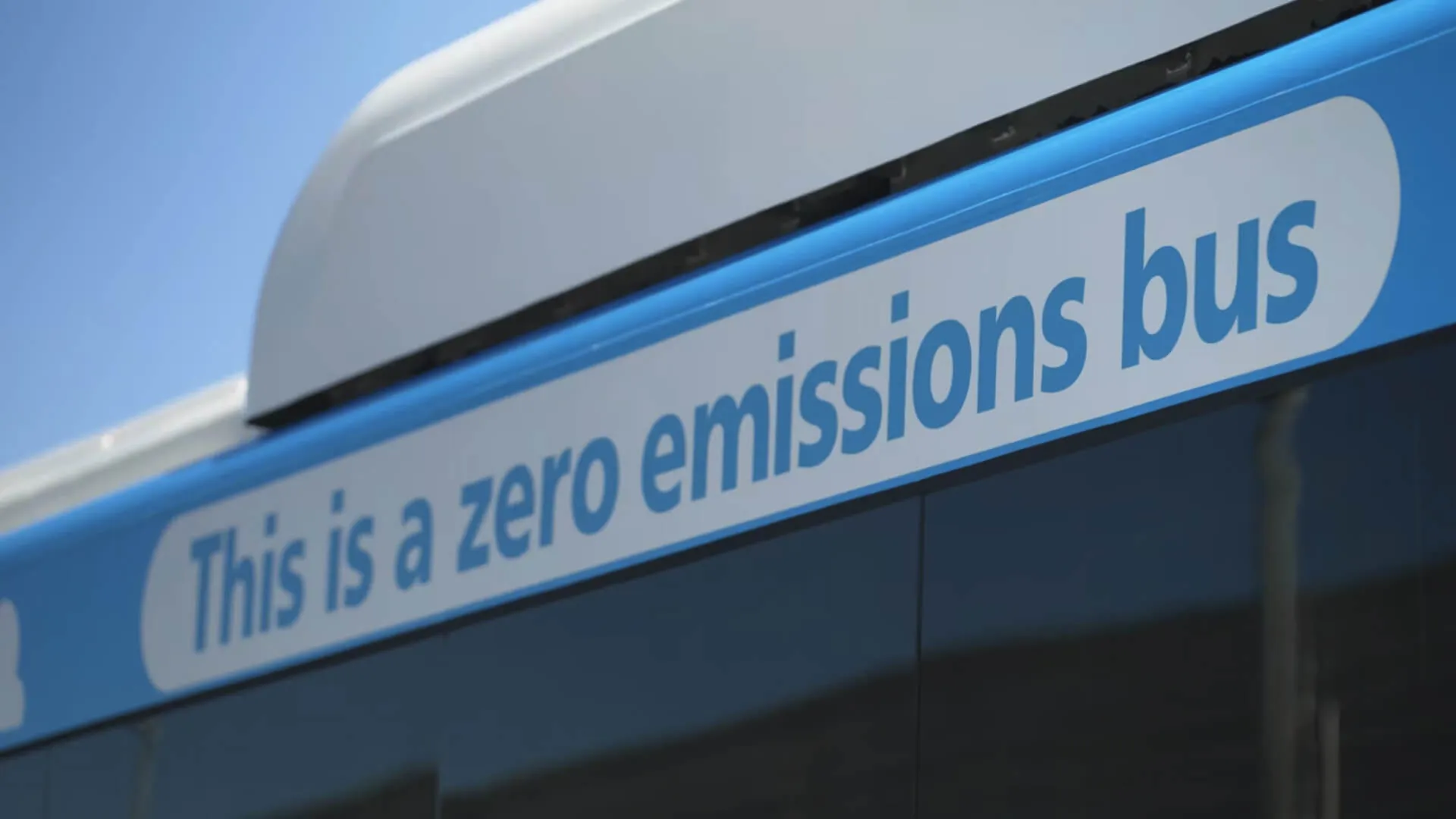 A close-up view of a bus with a sign that reads "This is a zero emissions bus" along the side, highlighting its environmentally friendly feature.