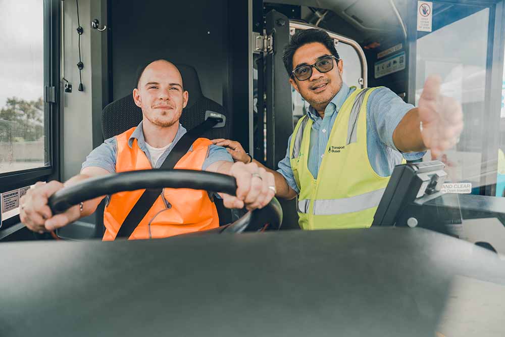 Trainee bus driver being coached by bus driver trainer