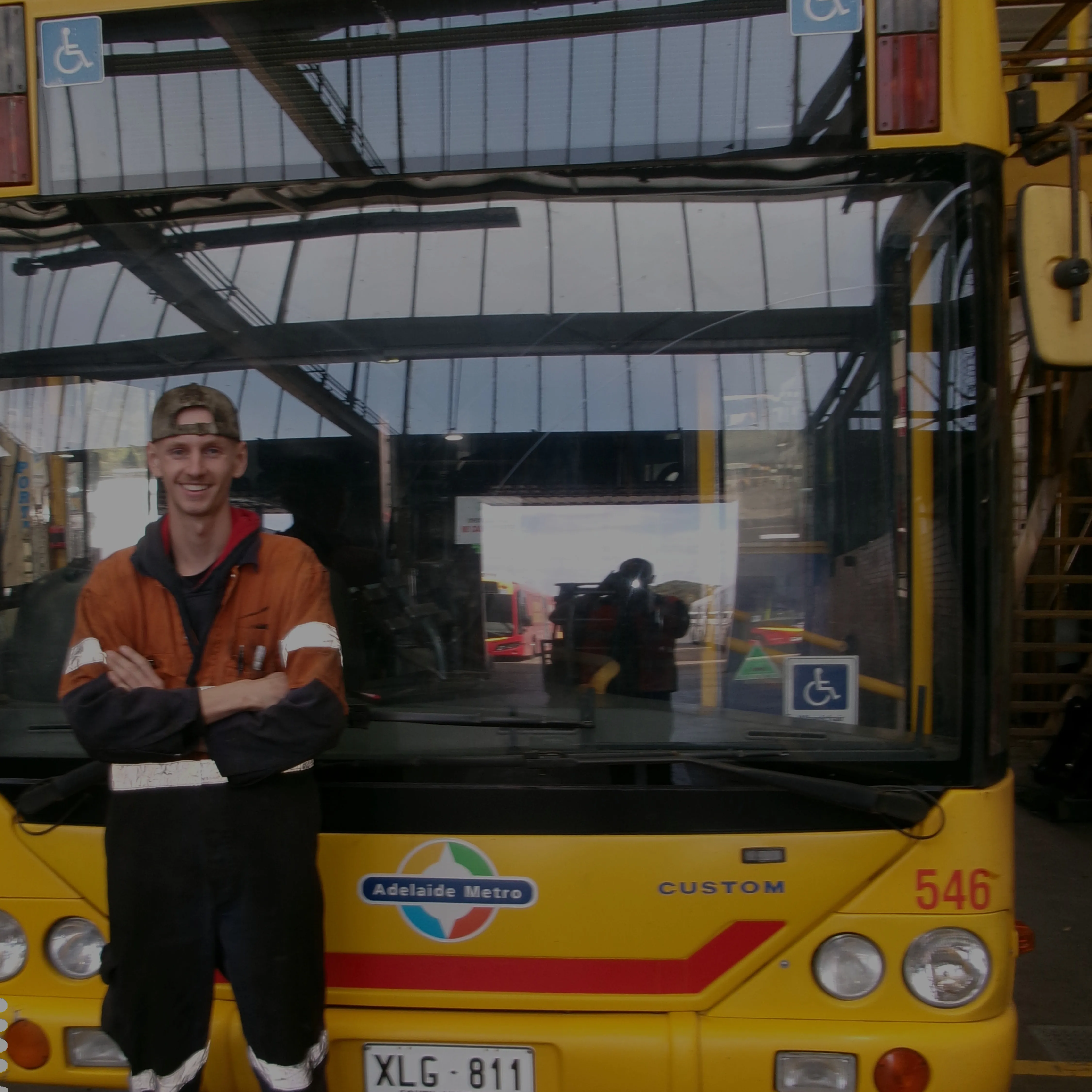 Mechanic stands in front of bus in workshop