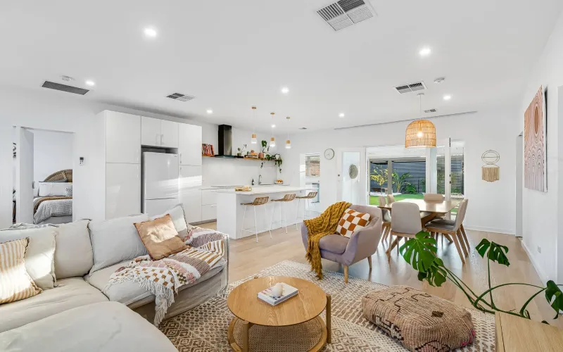 Modern living room with beige sofas, a turquoise fireplace, patterned rugs, and a hanging light fixture.