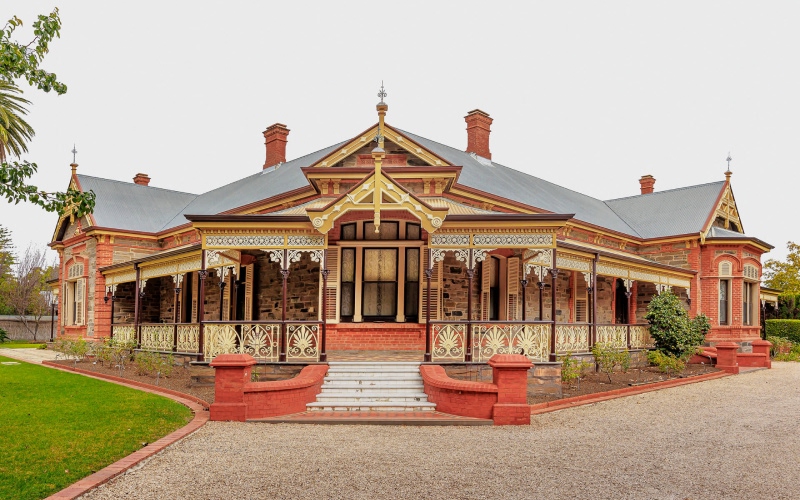 Close-up of heritage-style house verandah with ornamental timber and iron lacework details.