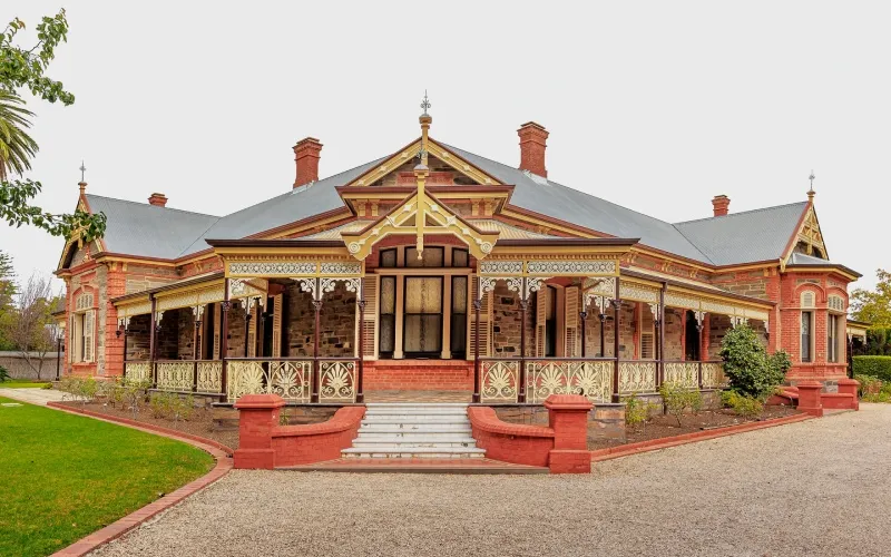 Close-up of heritage-style house verandah with ornamental timber and iron lacework details.