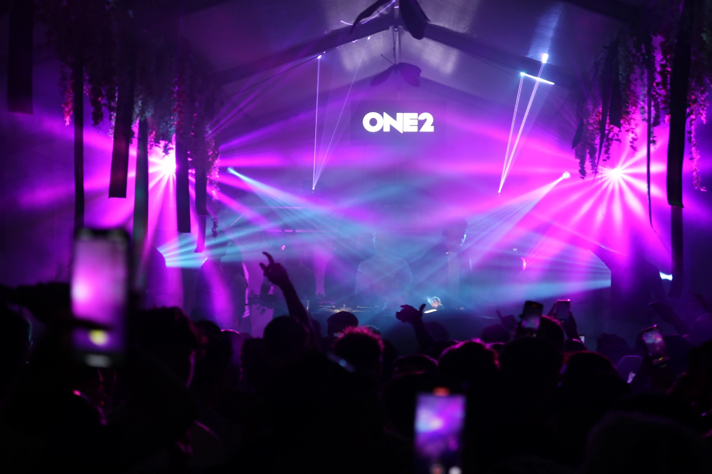 Crowd at a concert under purple and blue stage lighting