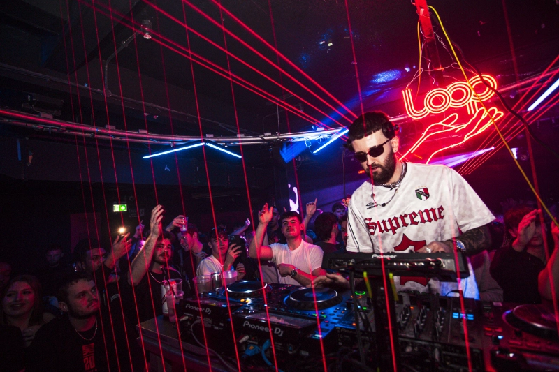 DJ performing on Pioneer equipment with a crowd under red laser lighting