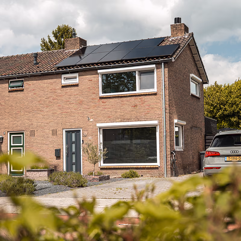 Twee-onder-een-kap woning met zwarte zonnepanelen op het dak en een geparkeerde Audi.
