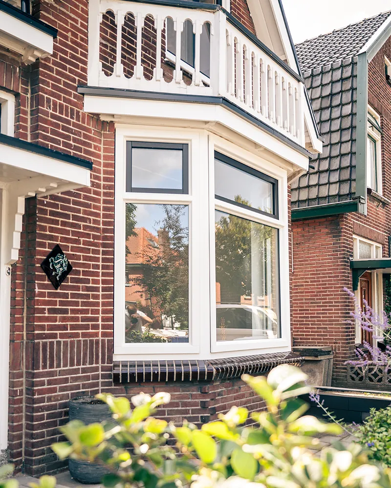 Wit kunststof draaikiepraam gecombineerd met vast glas in een erker