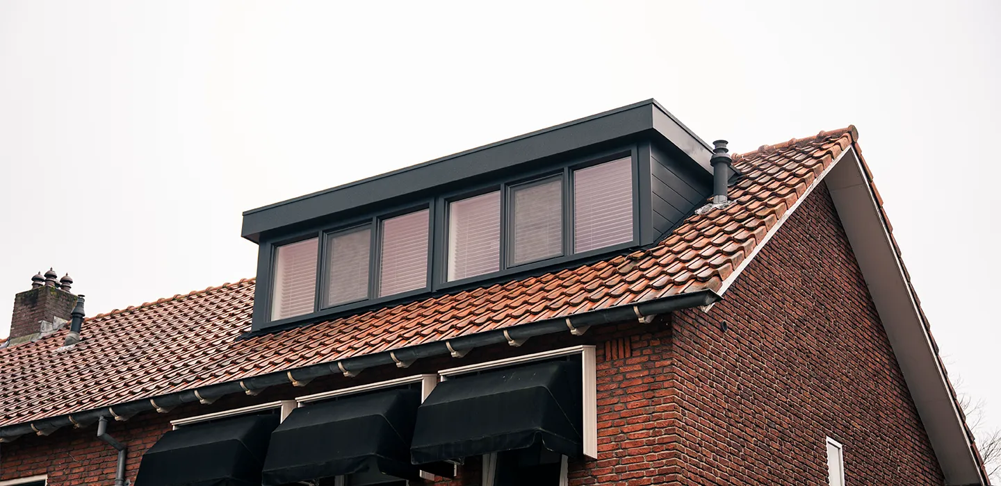 Antracieten dakkapel met zes ramen op een rood pannendak