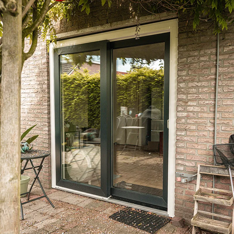 Antracieten kunststof schuifpui tussen tuinbegroeiing