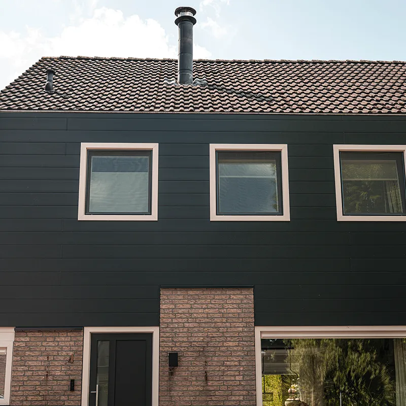 Antracieten Keralit gevelbekleding met drie ramen onder een rood pannendak