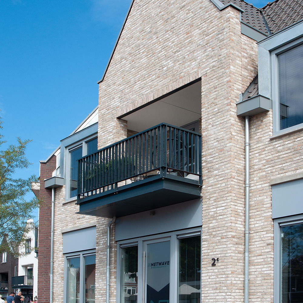 Antracieten VEKA kunststof kozijnen op een balkon boven een winkelpand