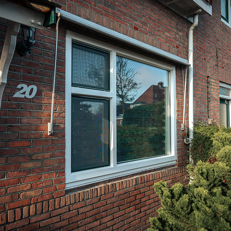 Wit kunststof draaikiepraam in een rode bakstenen gevel, voorbeeld van kunststof kozijnen bij een renovatie