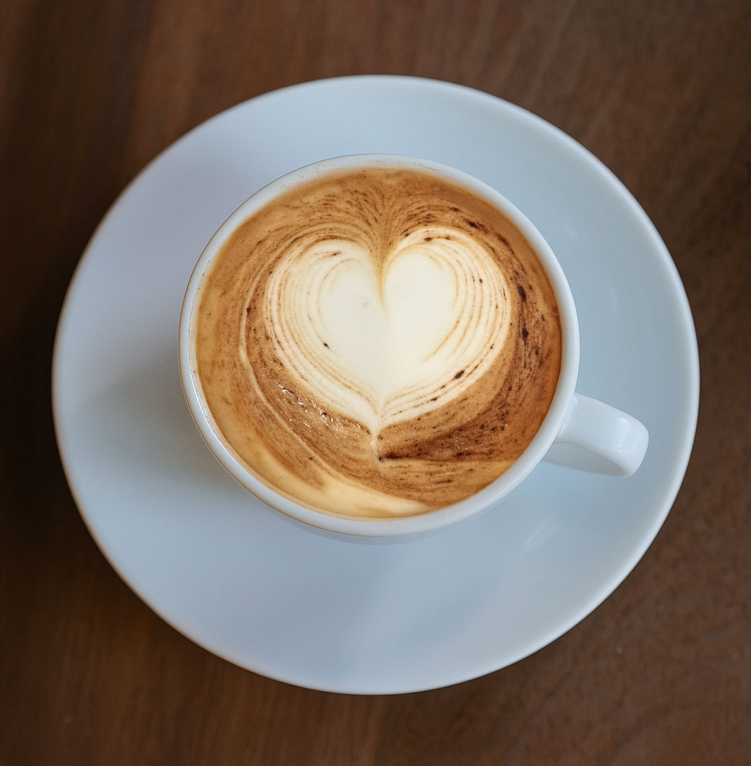 Nahaufnahme einer Kaffeetasse mit kunstvoller Blume im Milchschaum.