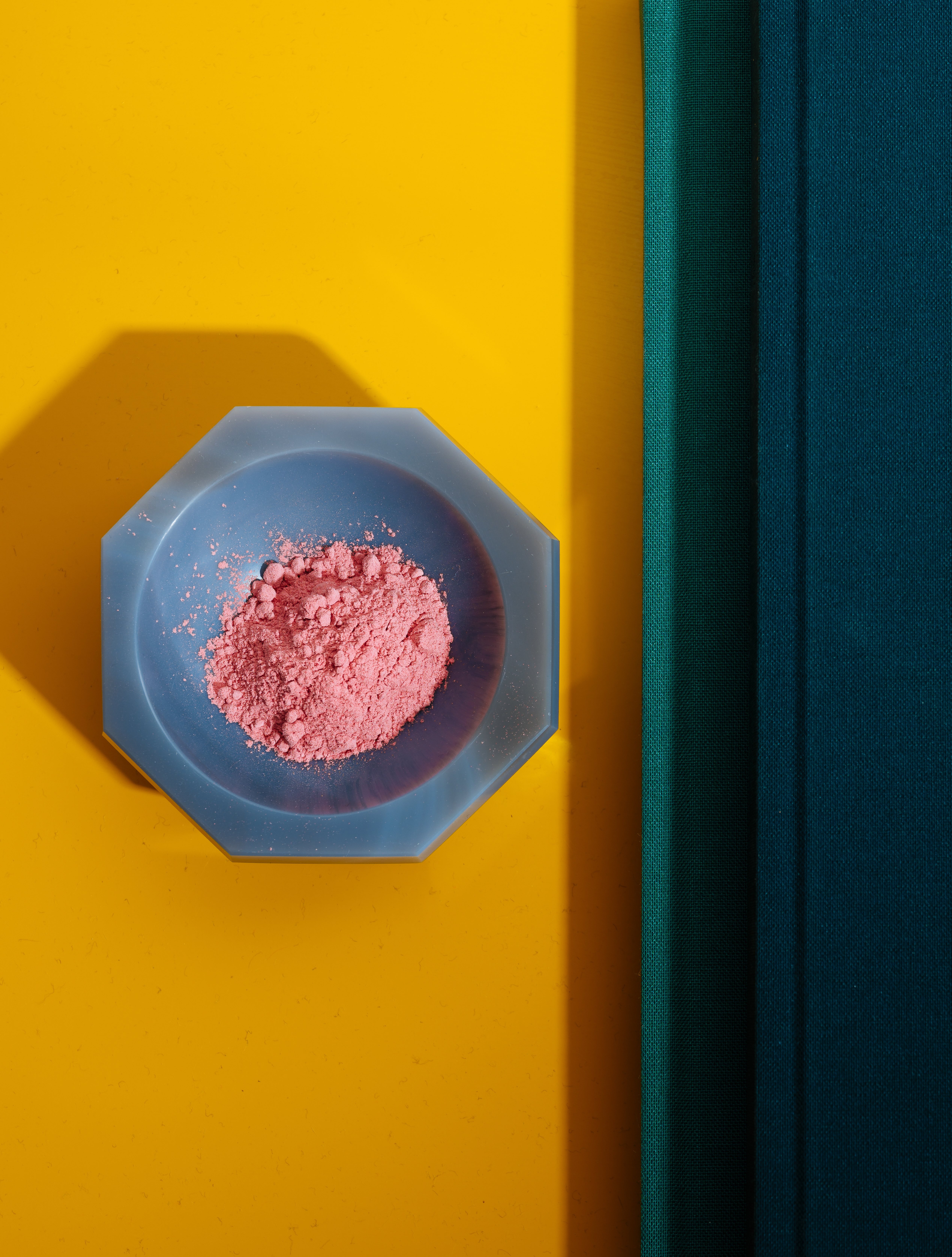 Coral red enamel powder in an agate mortar on a yellow and blue book