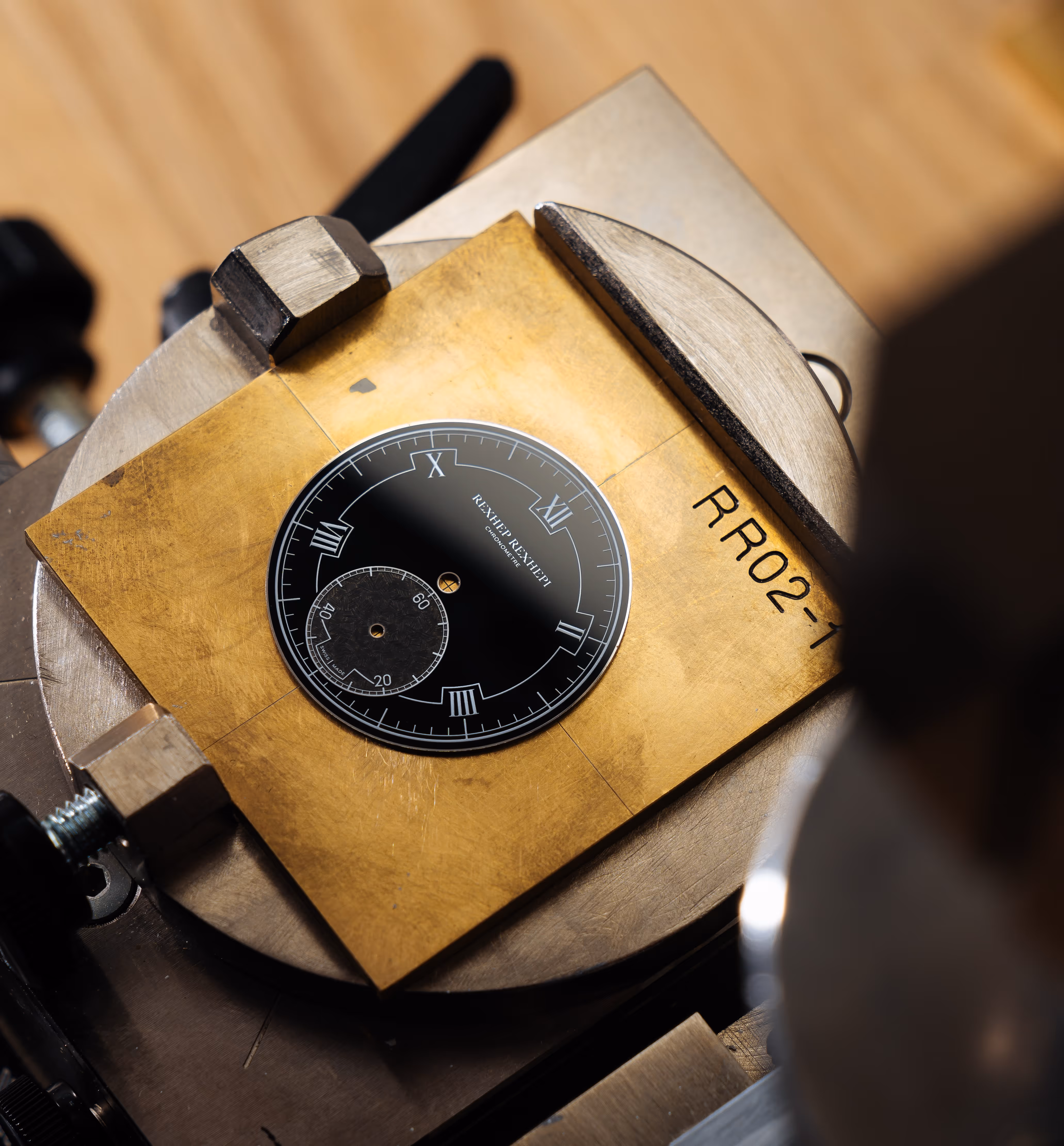 Black enamel watch dial mounted on a tampography machine during printing for RRCC II 