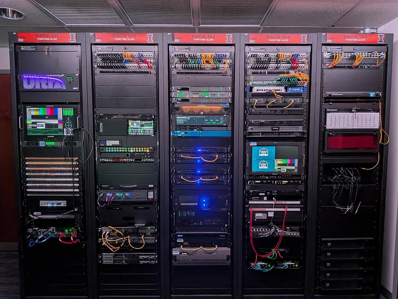 Full view of multiple broadcast equipment racks for Fighting Illini Productions, showing clean hybrid-2110 integration.