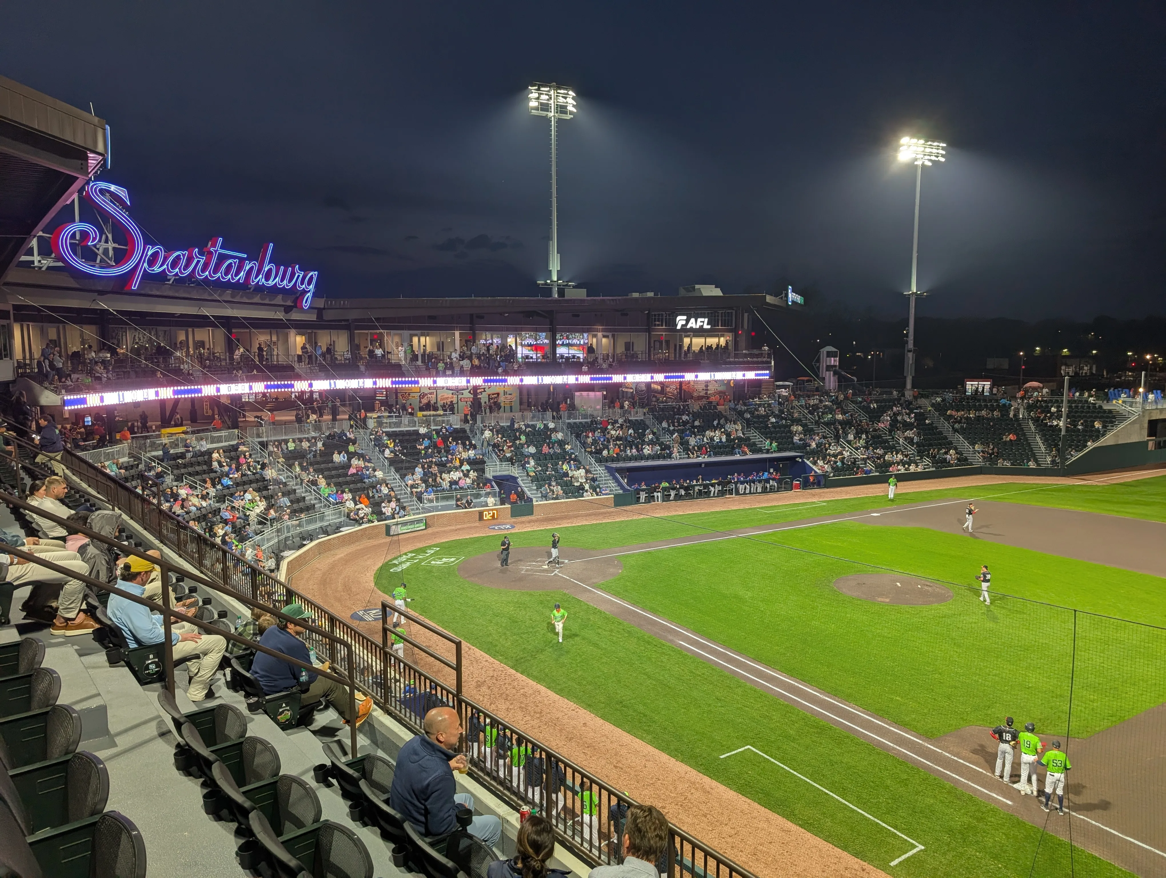 Wide shot of Fifth Third Park stadium at night with Spartanburg neon signage and illuminated baseball field.