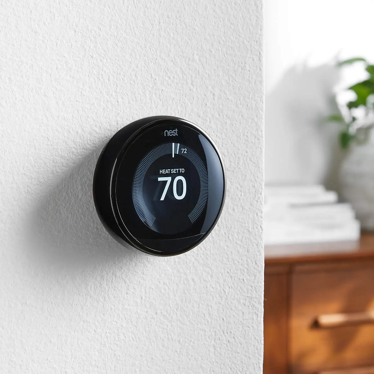 Black round Google Nest thermostat on wall.