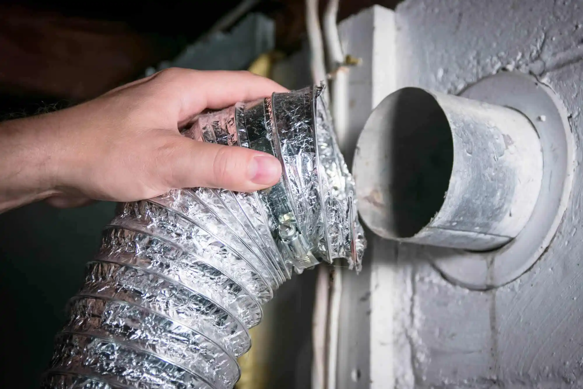 Connecting a dryer vent hose to wall.