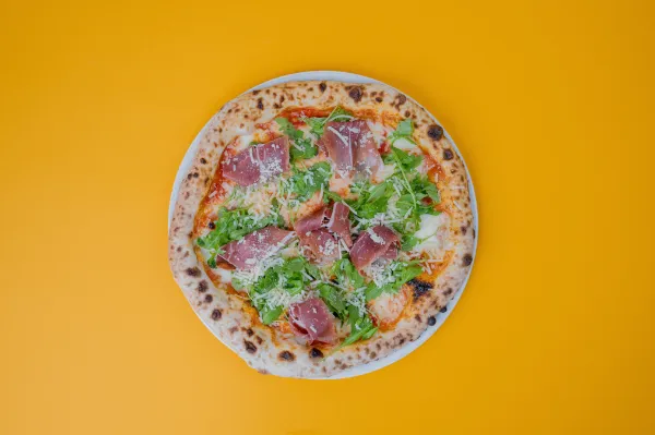 Neapolitan Parma & Rucola pizza with Prosciutto di Parma, fresh arugula, and Grana Padano on a tomato base.