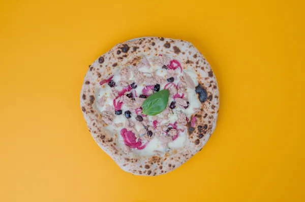 Italian Tonno e Cipolla pizza with tuna, red onions, black olives, and mozzarella on a white base.