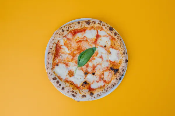 Freshly baked Neapolitan Margherita pizza with melted mozzarella, basil, and tomato sauce on a plate.