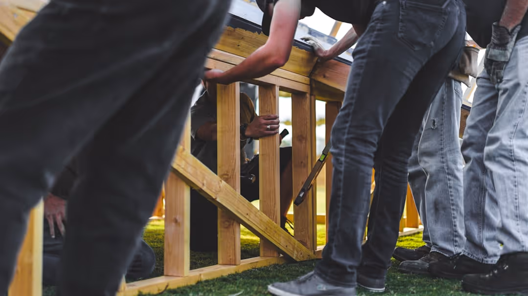 Professional fence installation crew working on a residential property with proper safety equipment and organized materials - fence builders in my area