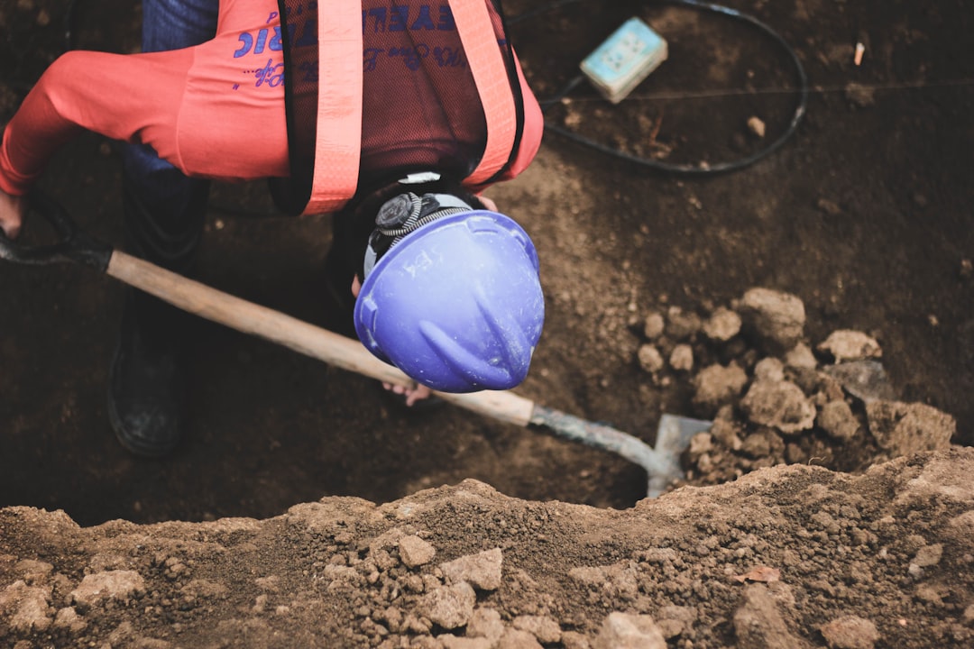 person digging post hole with proper technique - putting in a vinyl fence