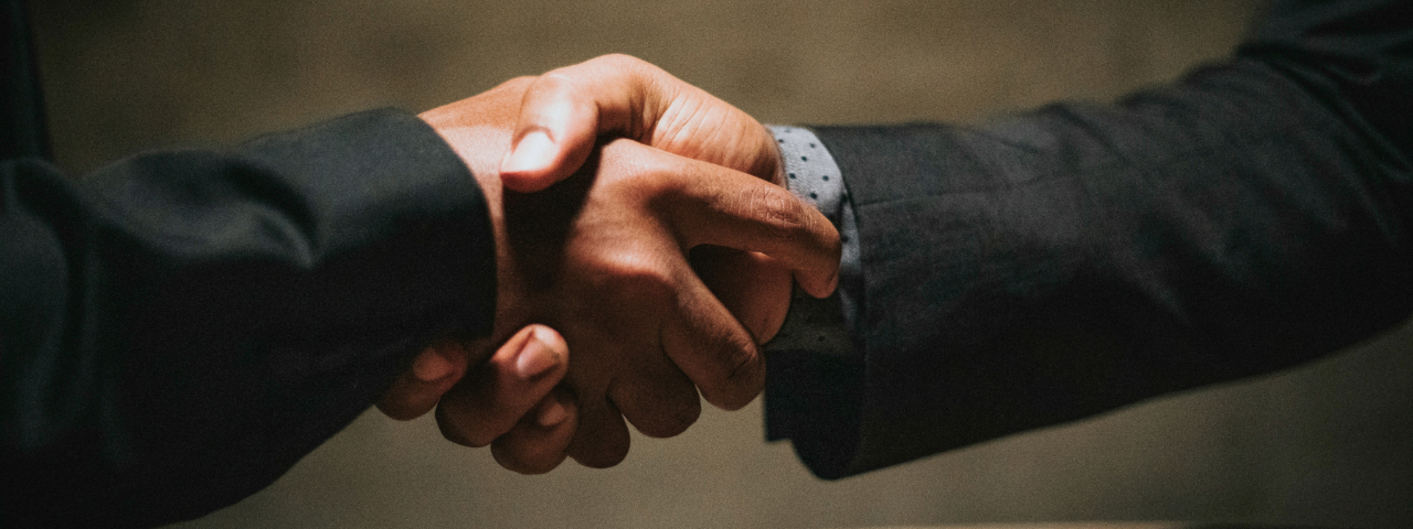 Close-up of two people in suits shaking hands, symbolizing trust, partnership, and professionalism.