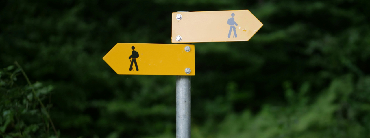 Two yellow road signs pointing in different directions, symbolizing decision-making paths.