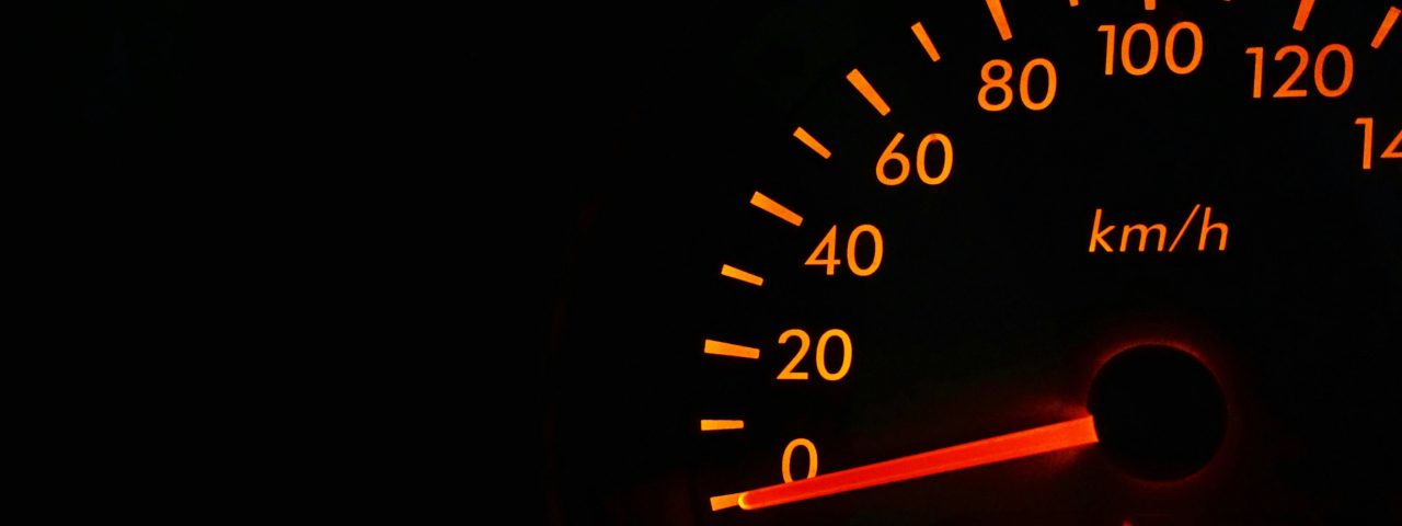Close-up of a car speedometer glowing orange, symbolizing performance speed.