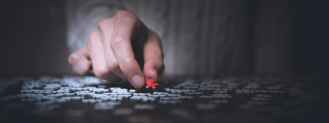 Hand placing puzzle piece to complete the picture, symbolizing Shopify fundamentals.