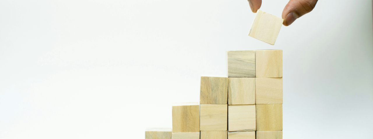 Wooden blocks stacked step by step, representing CRO prioritization with impact versus effort framework.