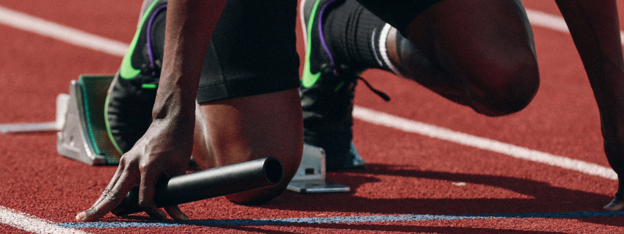 Athlete at the starting line holding a relay baton, symbolizing the discipline of starting and finishing CRO tests.