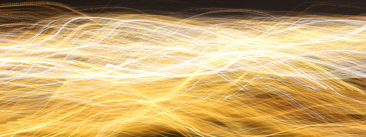 Abstract long-exposure light trails in yellow and white tones, symbolizing speed, energy, or digital data flow.