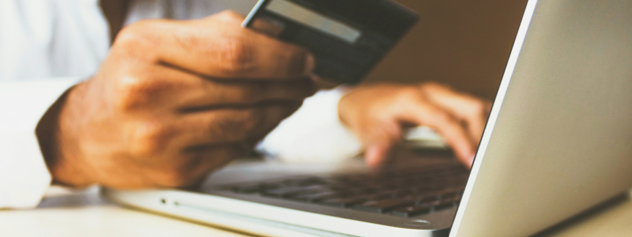 Close-up of a person using a laptop and holding a credit card.