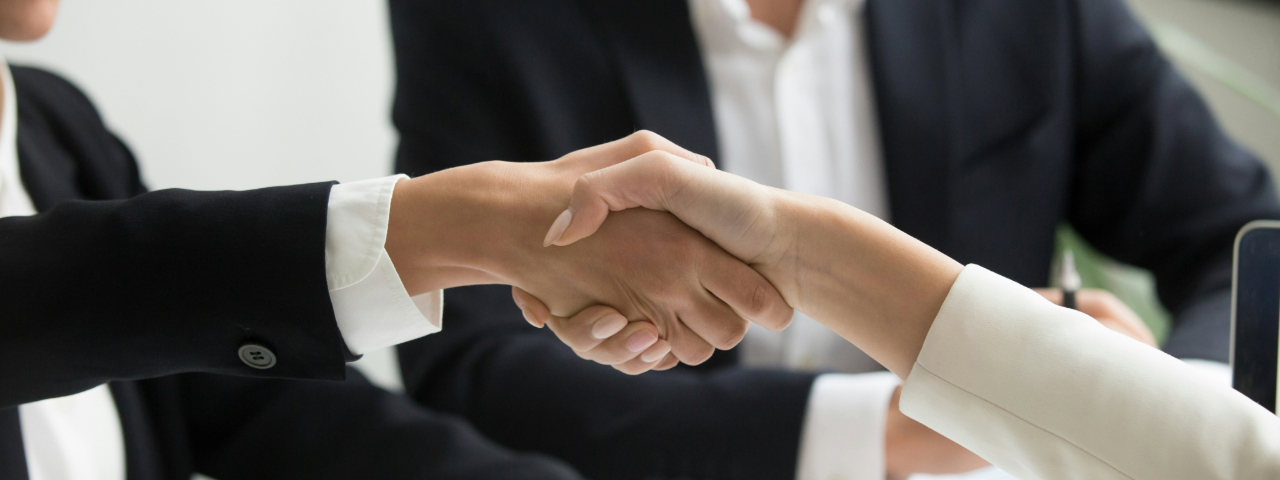 Close-up of a business handshake between two professionals wearing formal attire.