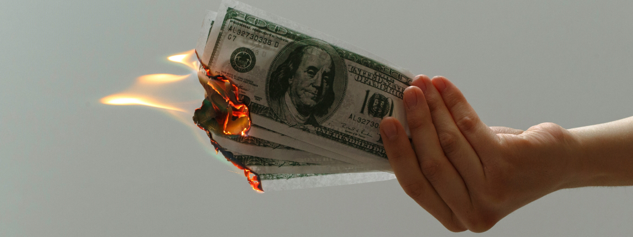 Burning money symbolizing high costs and risks of custom theme development.