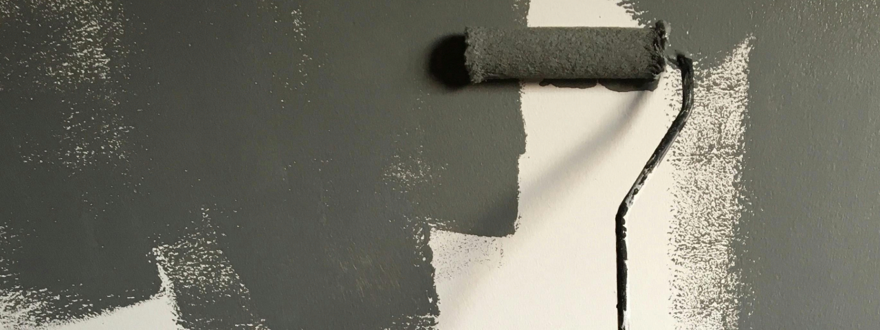 Hand painting a wall with a roller, symbolizing customizing a storefront.