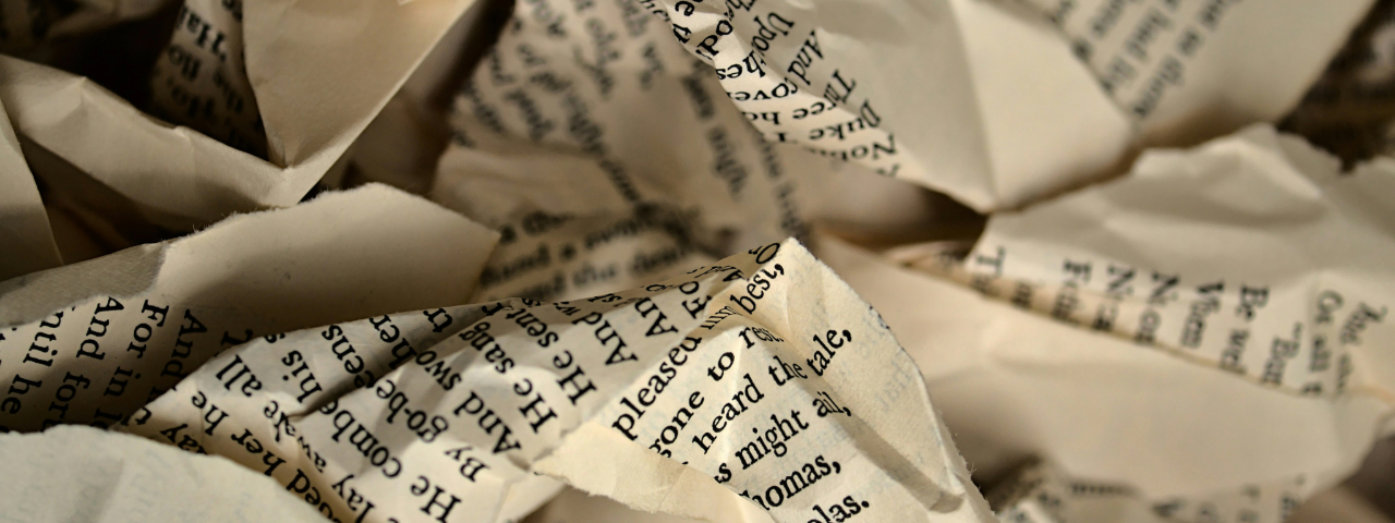 Close-up of crumpled pages with printed text, showing a mix of folded and torn paper.