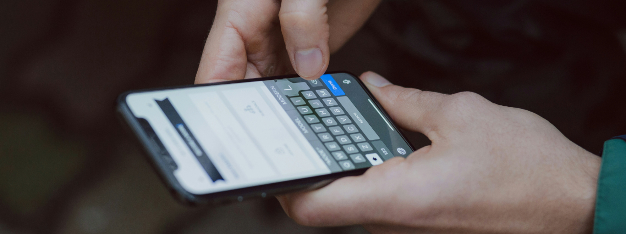 Close-up of hands typing on a smartphone screen.
