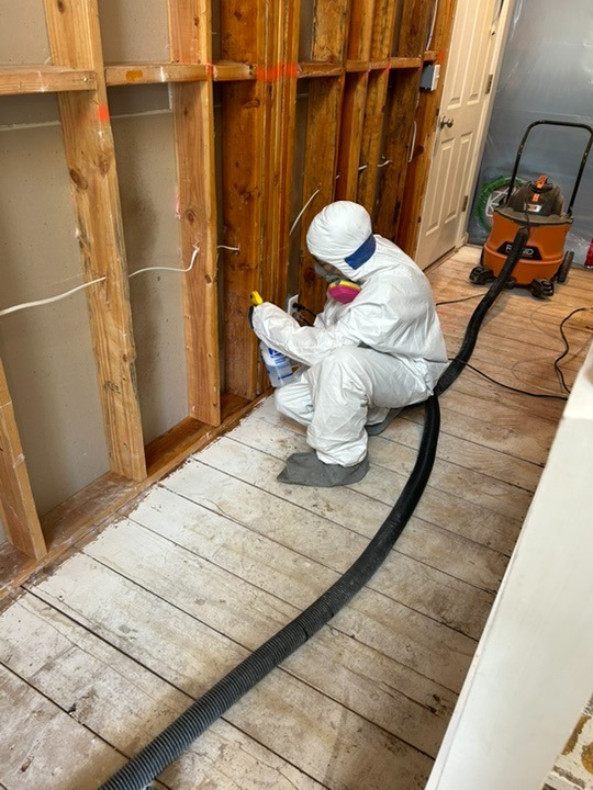 Mold removal technician in protective suit performing mold remediation and containment in an Orem, Utah Home