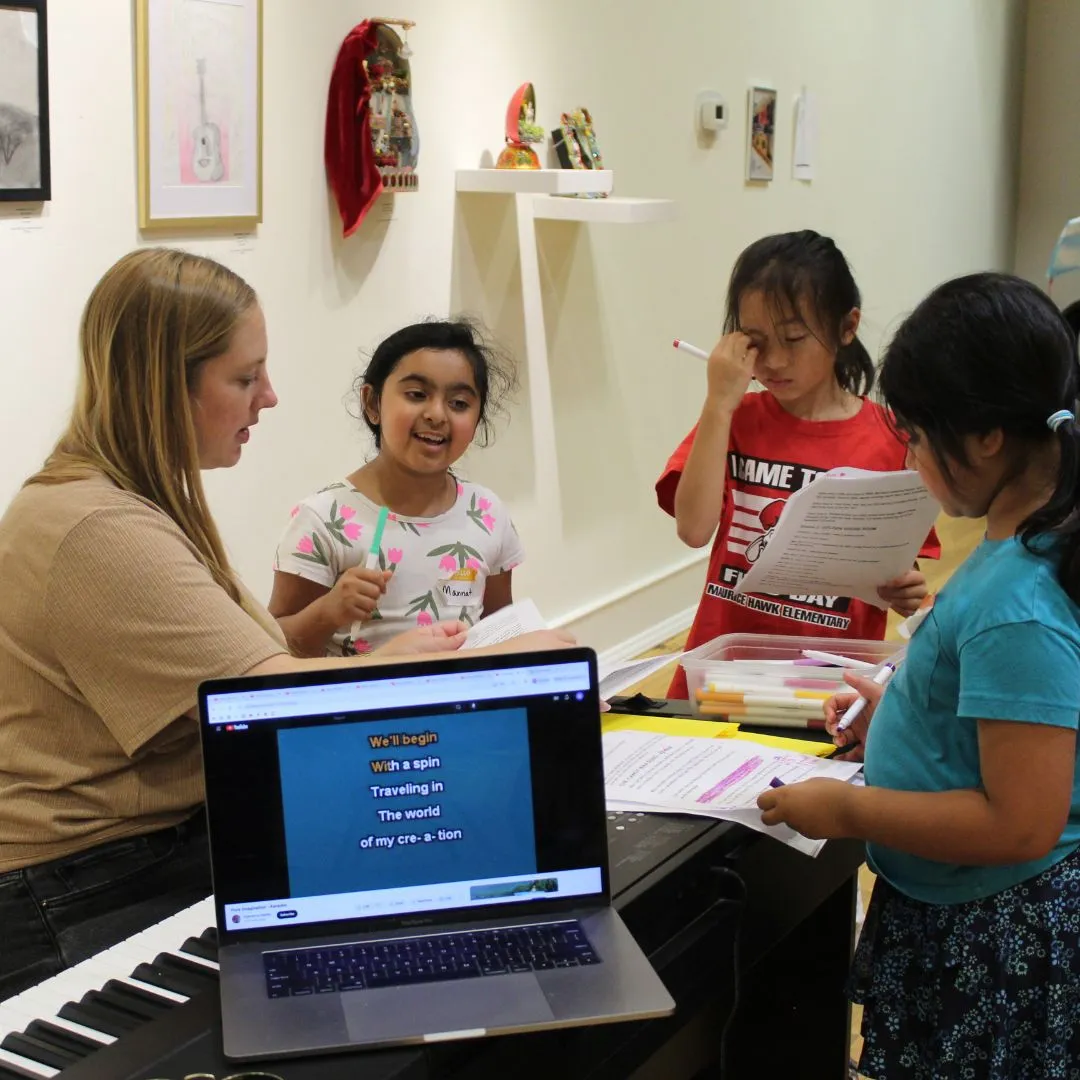 three girls with teacher practicing singing lines