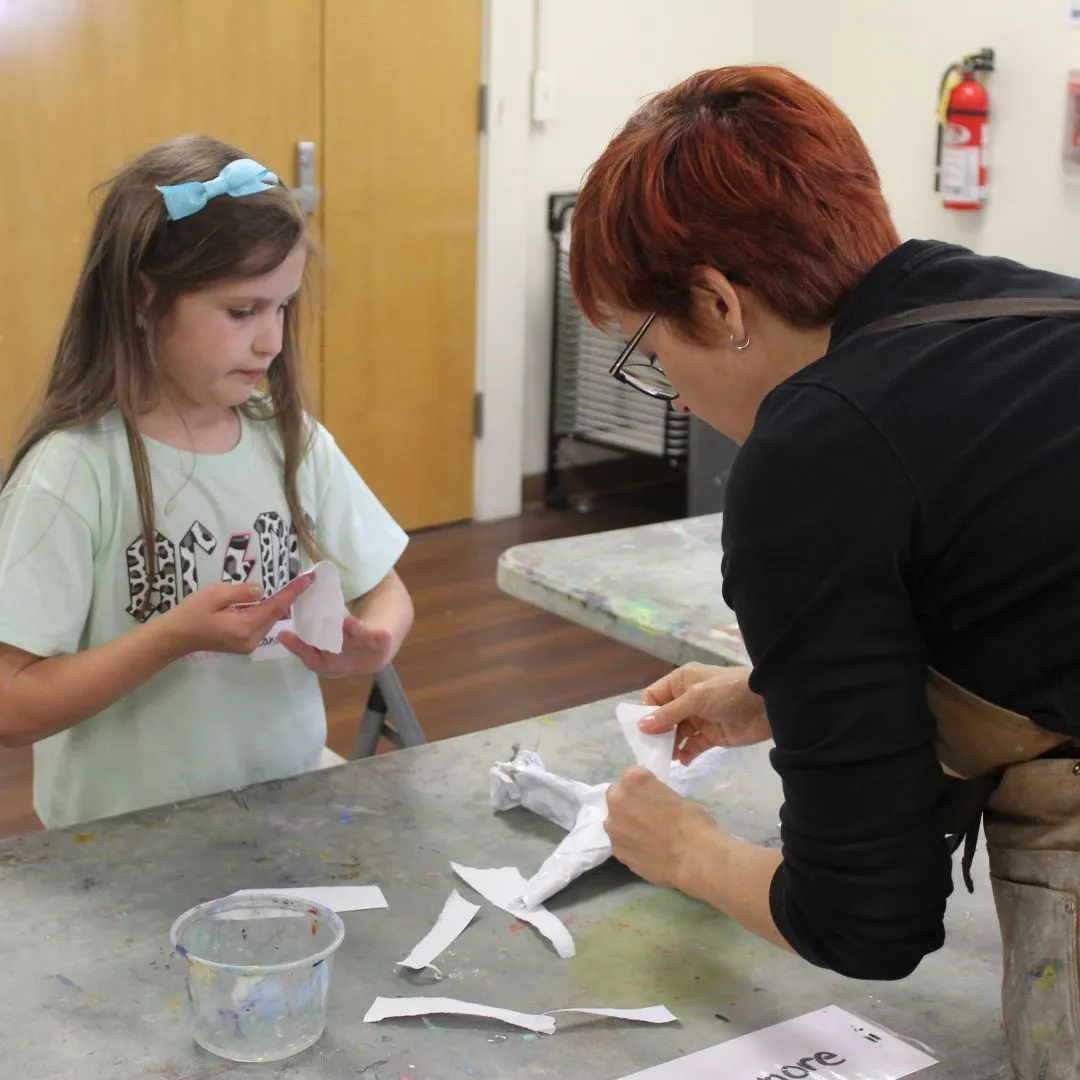 Teacher Katie works with student on paper mache
