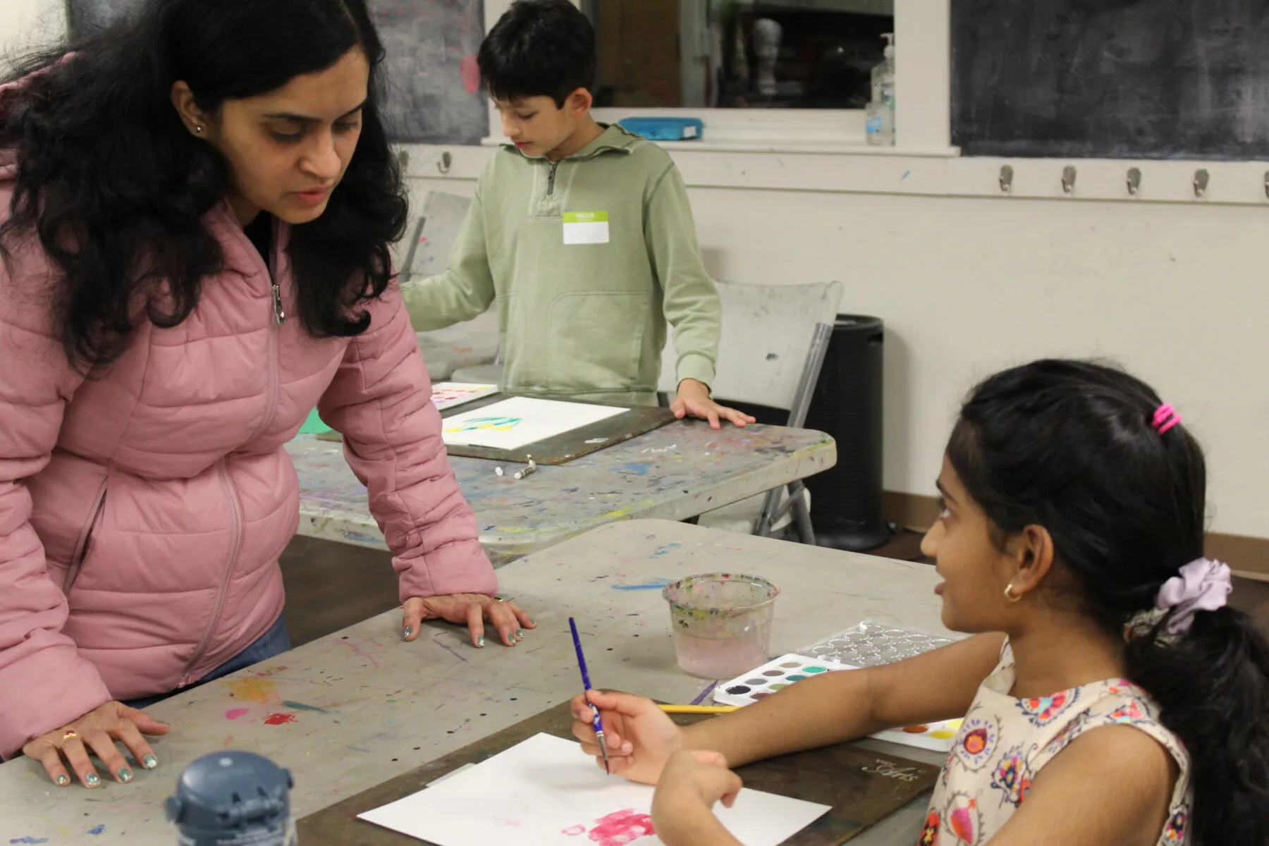 teaching artist Sarika instructs girl on watercolor painting