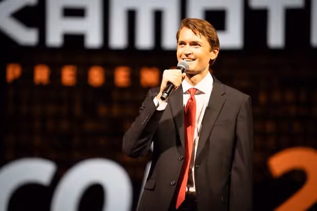 A person in a suit and tie holding a microphoneAI-generated content may be incorrect.