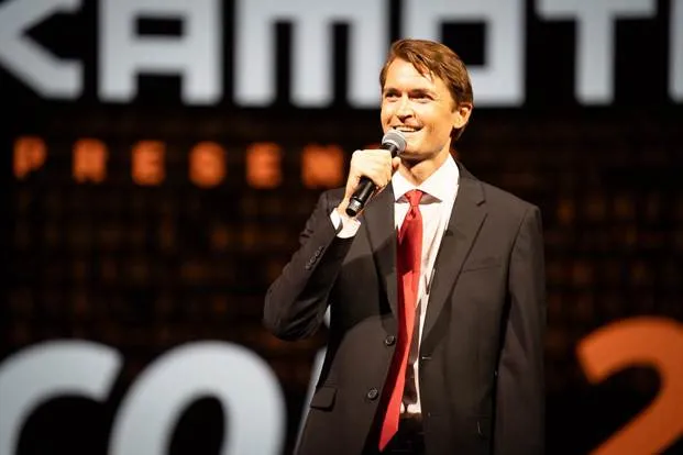 A person in a suit and tie holding a microphoneAI-generated content may be incorrect.