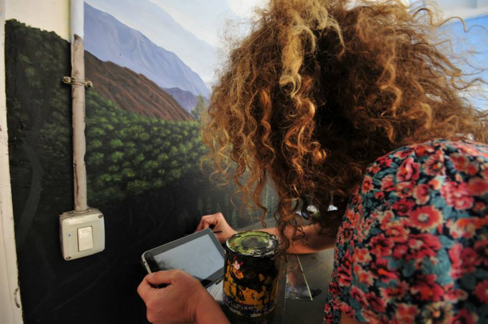 a curly woman painting plants on the wall