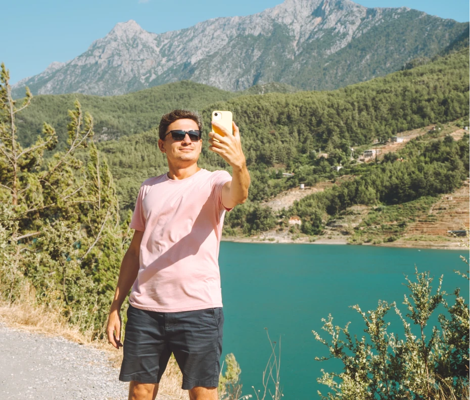 A guy taking a selfi with a lake background
