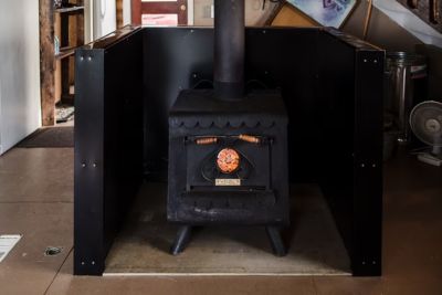 Small black wood-burning stove surrounded by black heat shield panels.