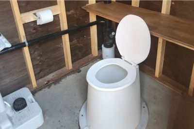 Outhouse toilet setup with a toilet paper holder.